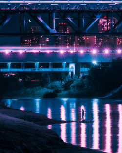 Illuminated bridge over river at night