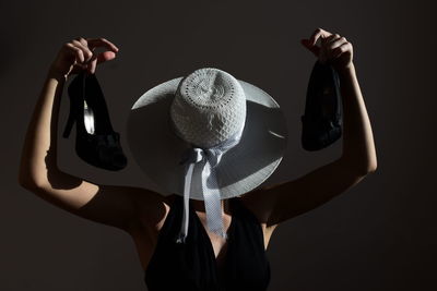 Midsection of woman with hat standing against gray background