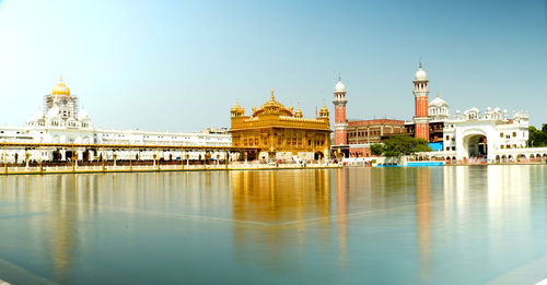 Reflection of temple in building against clear sky