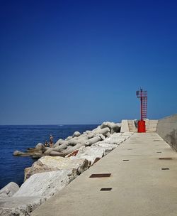 Lighthouse on beach against clear blue sky