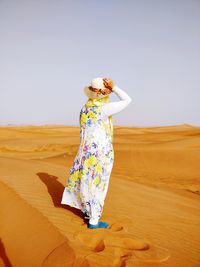 Full length of woman standing on sand against sky