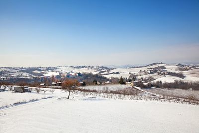 Snow covered field against clear blue sky