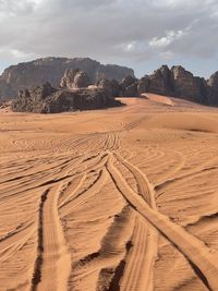 Scenic view of desert with tire tracks on the sand