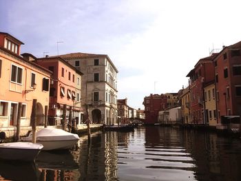 Boats moored in canal amidst buildings against sky