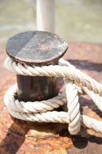 Close-up of rope tied to bollard at harbor