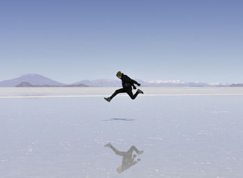 Man jumping over sea against clear sky