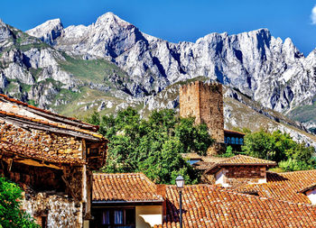 Houses and trees by mountains against sky