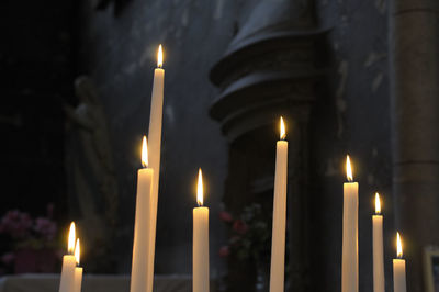 Lit candles in temple against building