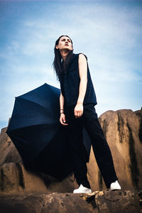 Full length of woman with umbrella standing against sky