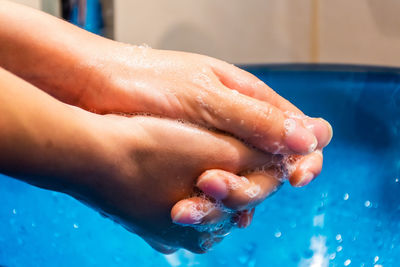 Close-up of person hand on wet swimming pool