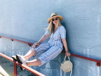 Portrait of woman sitting on railing against wall