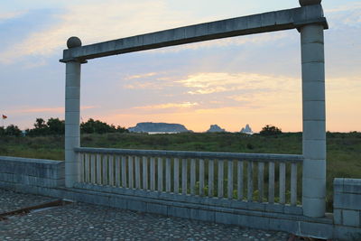 Metallic structure on field against sky during sunset