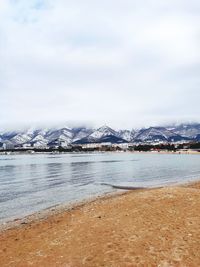 Scenic view of lake by snowcapped mountain against sky