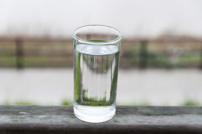 Glass of drinking water on railing against river