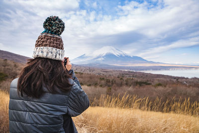 Woman standing on field against mountain during winter