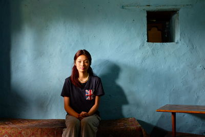 Portrait of young woman standing against wall