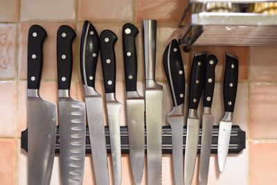 Close-up of knives against tiled wall in kitchen