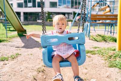 Full length of boy sitting on swing at playground