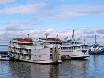 Boats moored at harbor against sky