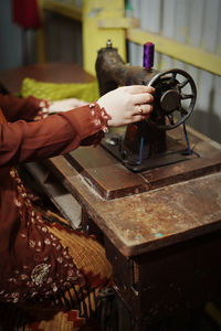 A woman's hand is sewing using an old sewing machine.