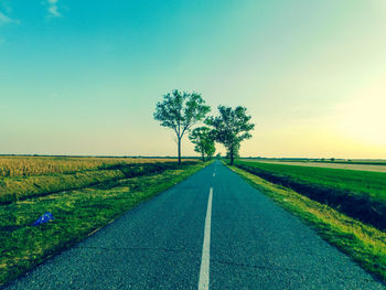 Road amidst field against clear sky