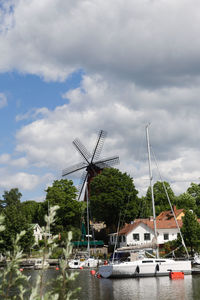 Sailboats moored in water against sky