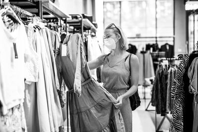 Mid adult woman wearing flu mask shopping in clothing store