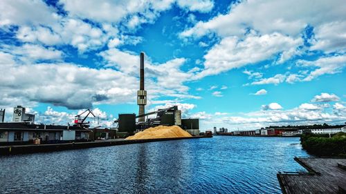 View of factory at harbor against blue sky