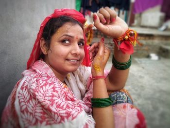 Smiling young bride looking up while sitting at outdoors