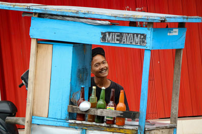 Portrait of smiling young man selling noodles soup