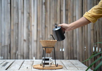 Cropped hand of woman pouring water in coffee cup