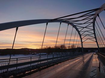 Bridge over road against sky during sunset