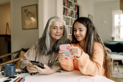 Girl teaching grandmother to use smart phone at home