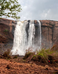 Scenic view of waterfall against sky