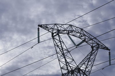 Low angle view of electricity pylon against cloudy sky