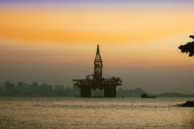 Silhouette built structure by sea against sky during sunset