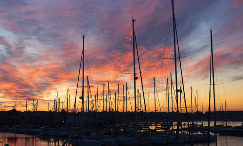 Sailboats moored at harbor during sunset