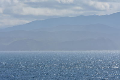 Scenic view of sea and mountains against sky