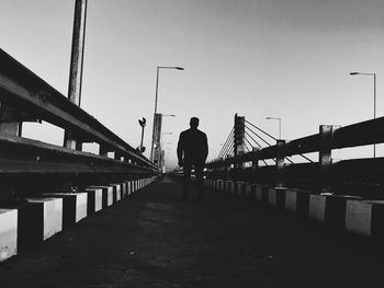 Man on bridge in city against clear sky