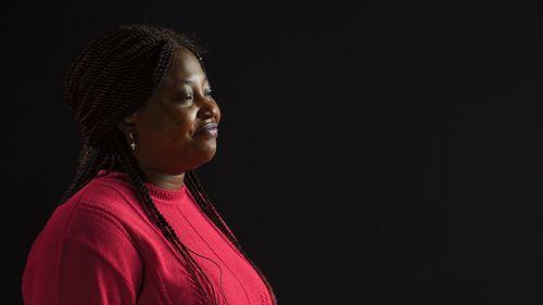 Young woman standing against black background