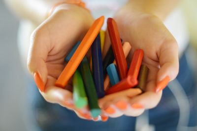 Close-up of hands holding multi colored crayons
