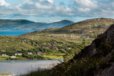 Scenic view of river by mountains against sky