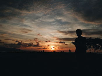 Silhouette man standing against sky during sunset