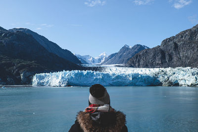 Rear view of woman standing on snow covered mountain against sky