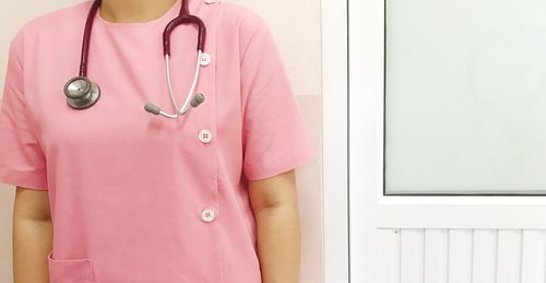 Midsection of woman with pink hair standing against wall