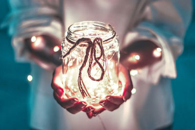 Midsection of person holding illuminated jar