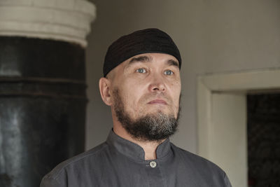 Close up portrait of serious senior asian man with light color eyes wearing skullcap. diversity 