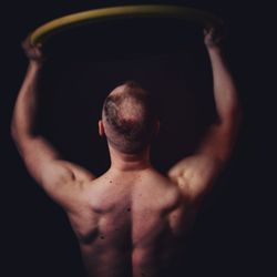 Midsection of shirtless man standing against black background