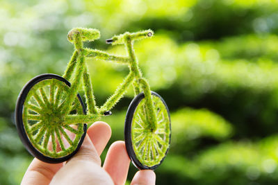 Close-up of person holding artificial green bicycle