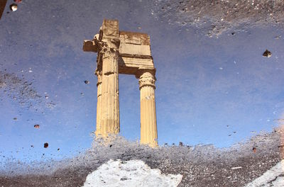 Reflection of old building in puddle